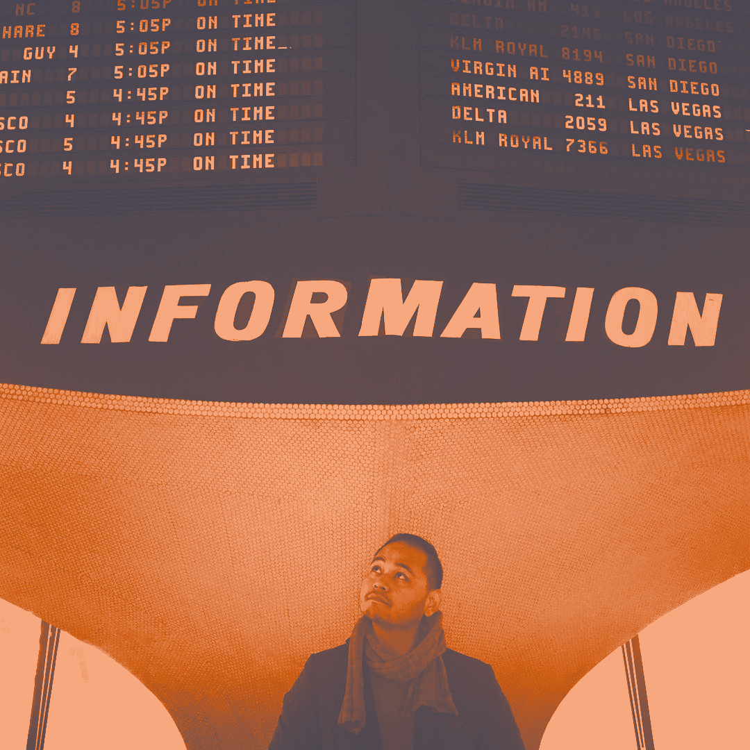 Photo of Matthew Marco standing at an Information sign at the TWA terminal at JFK International Airport